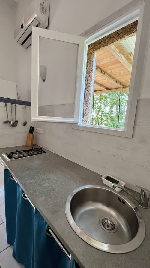 Cuisine aménagée de la villa Le Maquis Plage avec évier, cuisinière à gaz et vue par la fenêtre