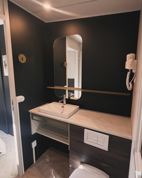Salle de bain moderne à la villa Le Maquis Plage à Poggio-Mezzana, avec murs noirs, plan de travail en bois et miroir