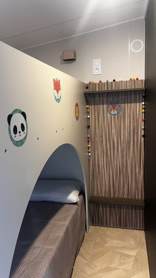 Chambre moderne de la villa Le Maquis Plage avec lit pod noir, armoire style nature, et décoration murale animalière fantaisiste
