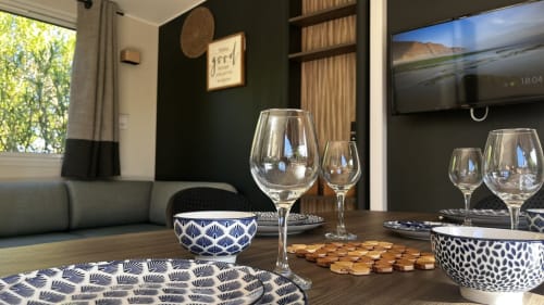Élégant salon de la villa Le Maquis Plage avec verres à vin, bols décorés et téléviseur écran plat à Poggio-Mezzana