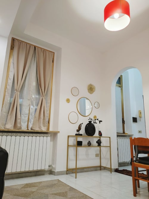 Interno moderno dell'appartamento della collezione THE V a Turate con lampada rossa a soffitto, specchio ad arco, mensole decorative e