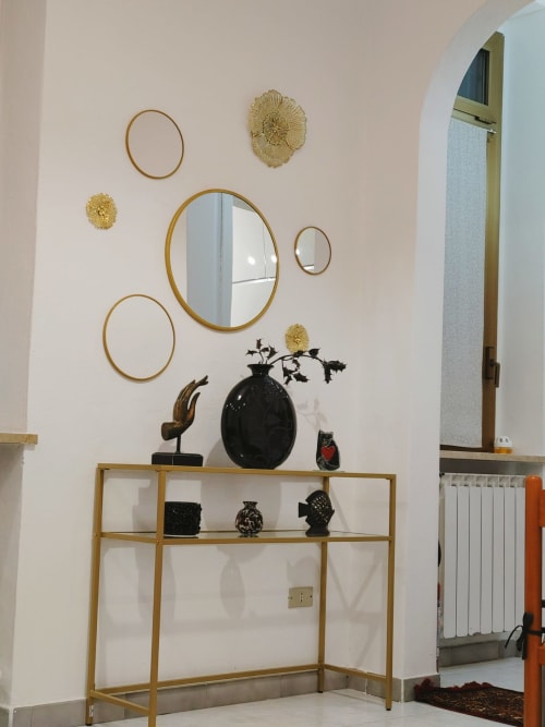 Arredamento moderno con specchi rotondi e accenti dorati sopra una scaffalatura in legno che espone oggetti decorativi neri