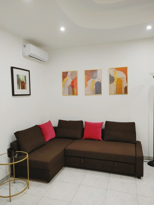 Divano marrone angolare con cuscini rossi nel soggiorno dell'Apartment Mazzini at THE V Collection, Turate