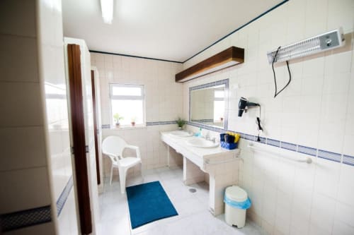 Banheiro moderno da Home Alliance B&B em Bombarral com duas pias, espelho, banheira, tapete azul e azulejos claros