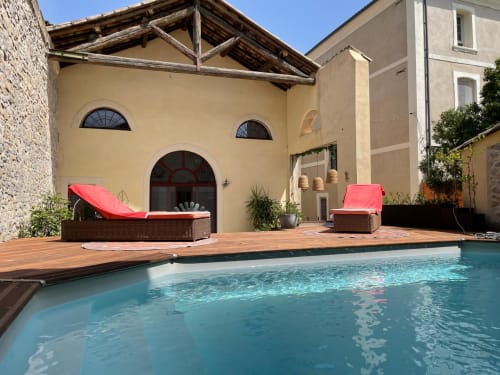 Piscine et terrasse de La Conciergerie De Franck à Boissières, avec chaises longues et bâtiments ocre