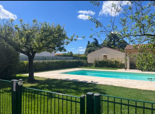 Piscine turquoise avec terrasse à La Conciergerie De Franck à Boissieres, entourée d'arbres et de verdure