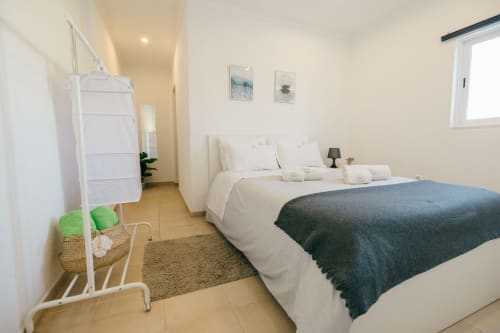 Bright bedroom at Tree House villa in Sesimbra with queen bed, white linens, dark throw, and modern amenities