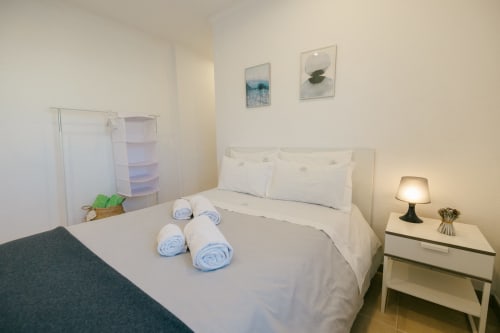 Bright bedroom at Tree House villa in Sesimbra with white bed, blue rolled towels, bedside lamp, and modern furnishings