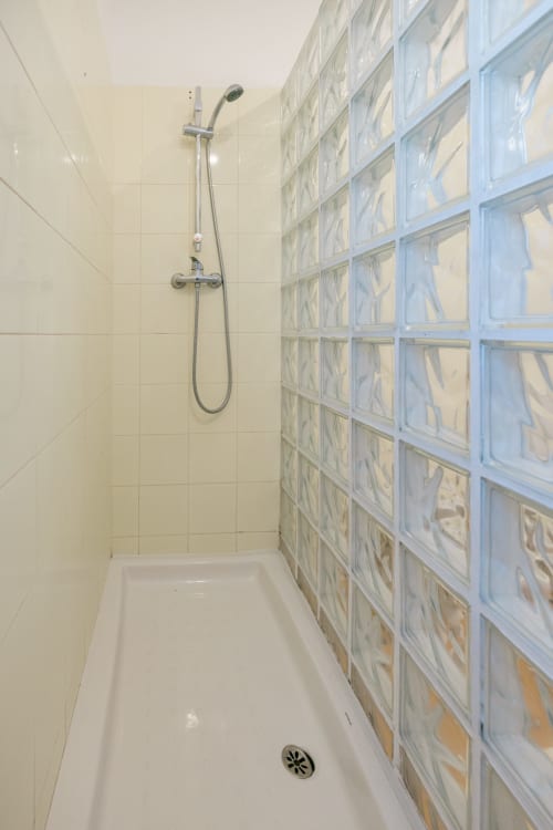 Modern shower with chrome handheld showerhead and white tile walls at Figueira House villa, Tree House Sesimbra