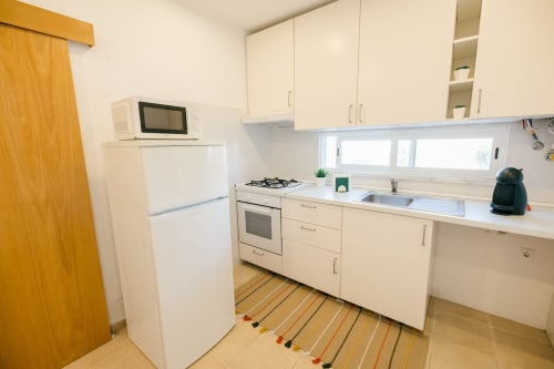 Modern kitchen in Figueira House villa at Tree House Quinta Do Conde, Sesimbra with white cabinets, gas stove, and striped