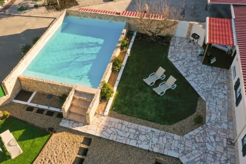 Aerial view of Figueira House villa at Tree House with turquoise pool, manicured garden, lounge chairs, paved patio and