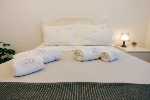 Neatly arranged white towels and rolled linens on a bed at Tree House villa in Sesimbra, Portugal