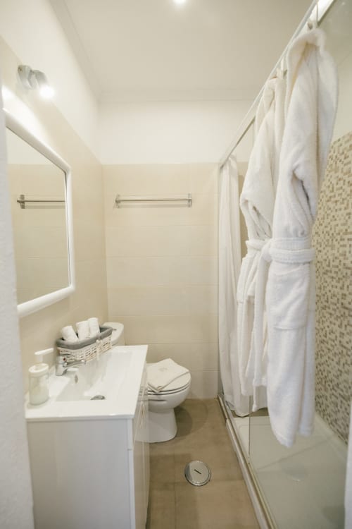 Clean bathroom at Tree House villa Casa Laranjeira with white sink, toilet, shower, and white towels in Sesimbra