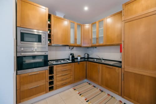 Modern kitchen with wooden cabinets, stainless steel appliances, and black countertops at Casa Laranjeira villa