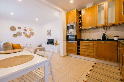 Modern kitchen and dining area in Casa Laranjeira villa at Tree House, Sesimbra with wooden cabinets and open living space
