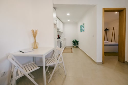 Modern open-plan kitchen and dining area at Limoeiro House villa, Tree House Sesimbra, with white cabinetry and wooden chairs