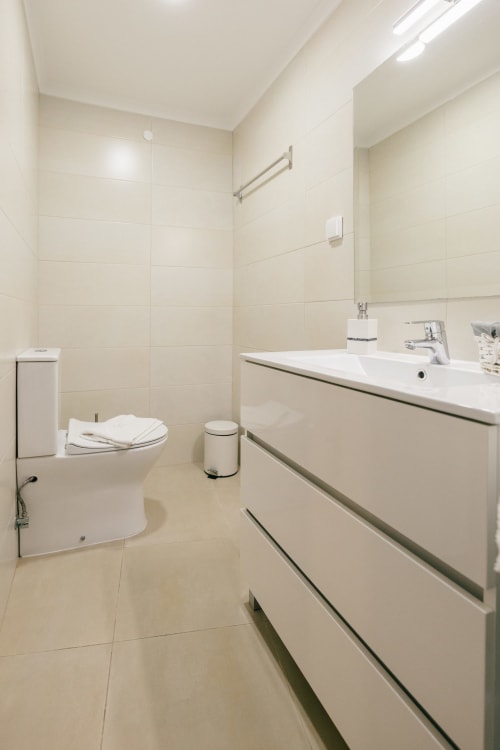 Modern bathroom at Tree House villa in Sesimbra with white sink, toilet, and cream tile walls