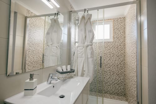 Modern bathroom at Tree House villa in Sesimbra with walk-in shower, white sink, mirror, and mosaic tile accents