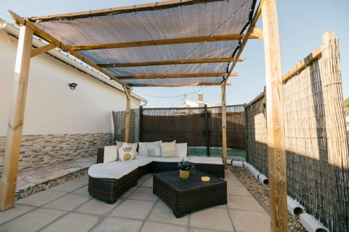 Limoeiro House villa terrace with wooden pergola, black rattan seating, and shade screens in Sesimbra