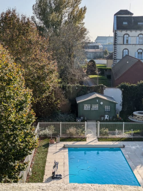 Manoir Saint Joseph pool view with heated outdoor swimming pool, manicured gardens, and historic stone buildings in Sens,
