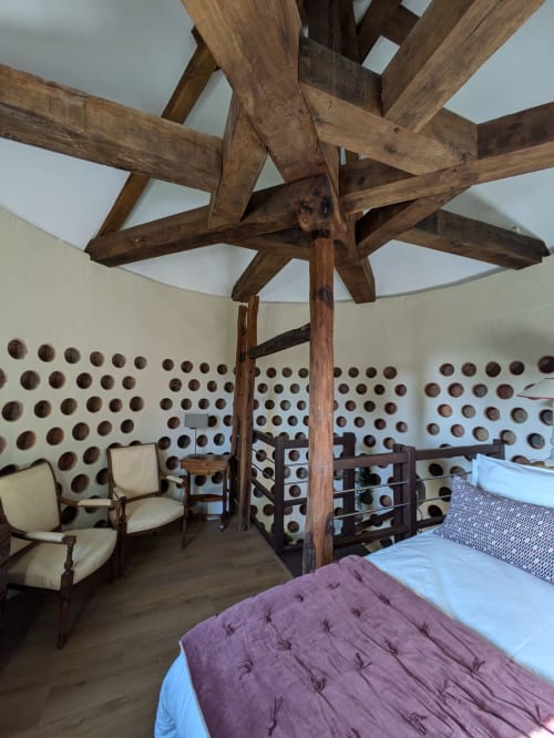Dovecote bedroom at Manoir Saint Joseph with exposed wooden beams, pottery wall display, and period furniture in Sens, France