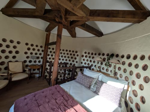 Historic bedroom in Dovecote at Manoir Saint Joseph, Sens, featuring rustic wooden beams and decorative plate wall displays