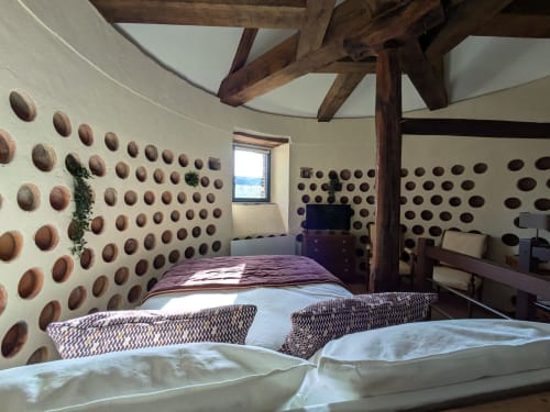 Dovecote bedroom at Manoir Saint Joseph, Sens, with exposed wooden beams, decorative wall niches, and garden views.