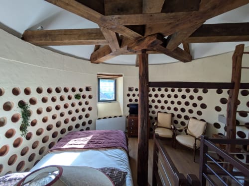 Historic bedroom in dovecote at Manoir Saint Joseph Sens with wooden beams and clay pot wall decoration