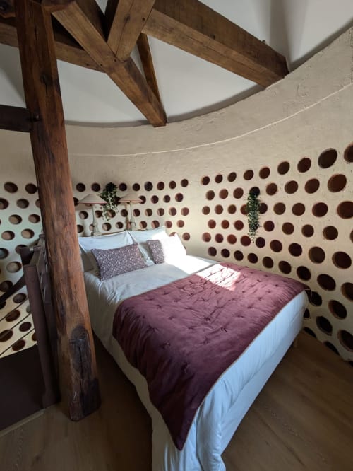 Bedroom in Dovecote at Manoir Saint Joseph, Sens with wooden four-poster bed, burgundy bedding, and circular ventilation