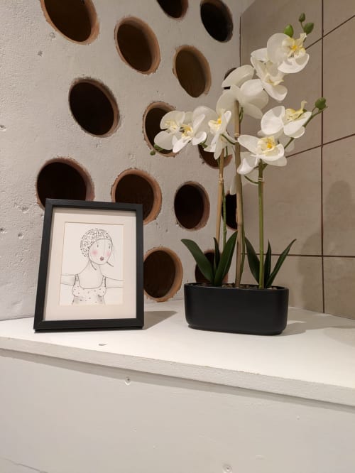 Bedroom shelf at Manoir Saint Joseph with white orchids in black pot, framed sketch, and decorative wall holes in Sens