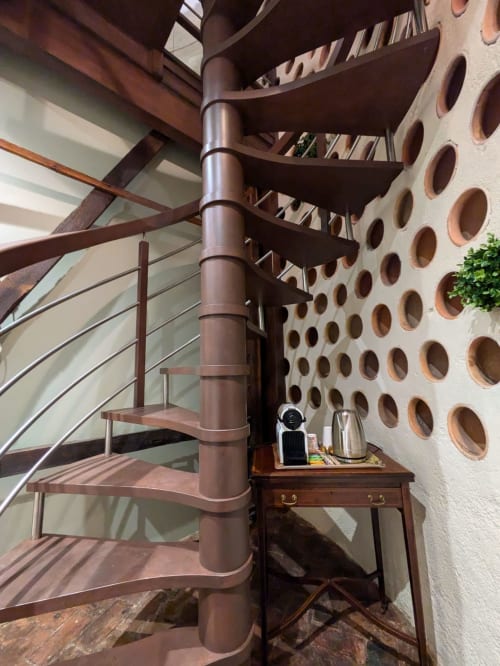 Modern spiral staircase in Manoir Saint Joseph's Dovecote bedroom in Sens, France, with glass railing and circular window