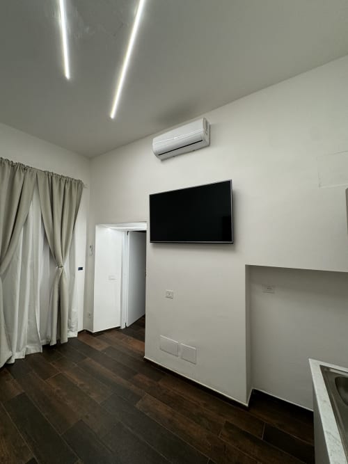 Camera moderna di Enjoy House Bracciano con TV a parete, aria condizionata e legno scuro