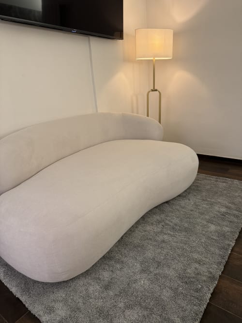 Elegante divano bianco curvo con lampada da terra nella zona soggiorno dell'appartamento Enjoy House Bracciano
