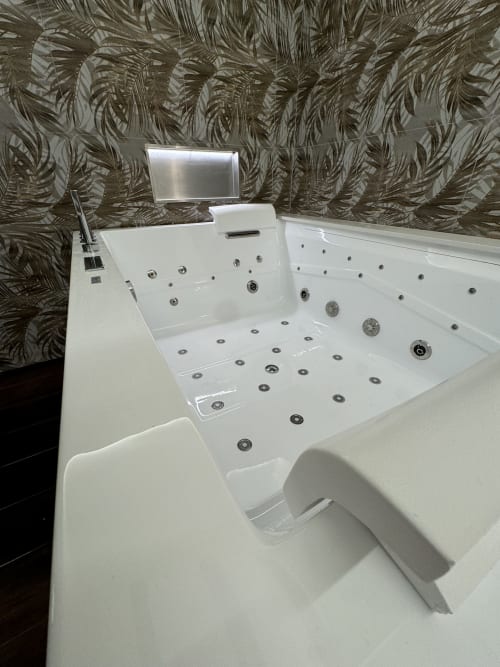 Lussuosa vasca idromassaggio bianca con getti d'acqua e TV a schermo piatto presso Enjoy House Bracciano, appartamento a Bracciano Italia