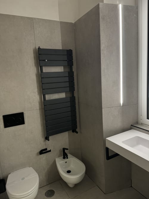 Moderno bagno presso Enjoy House Bracciano con scaldasalviette a muro, bidet e wc bianchi, rivestimento in stile marmo