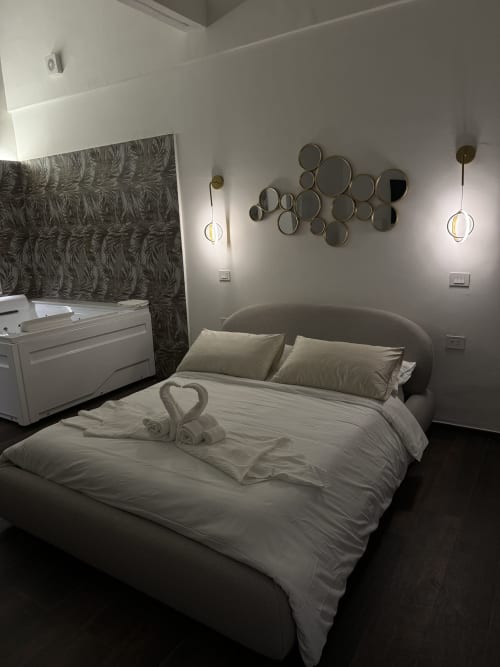 Camera moderna presso Enjoy House Bracciano con letto, specchi decorativi, lampade a sospensione e arredi bianchi