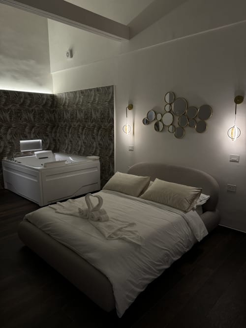 Camera moderna presso Enjoy House Bracciano con letto, vasca idromassaggio e specchi decorativi a parete