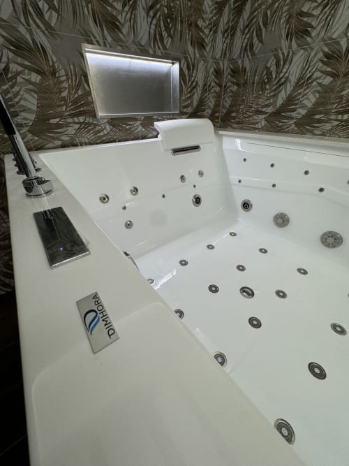 Vasca idromassaggio lussuosa con getti d'acqua presso Enjoy House Bracciano, con TV e carta da parati tropicale