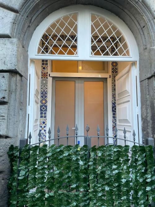 Porta ad arco bianco con decorazioni di maioliche e finestre a griglia presso San Nicola Suite Mini Apartments a Sorrento, Italia