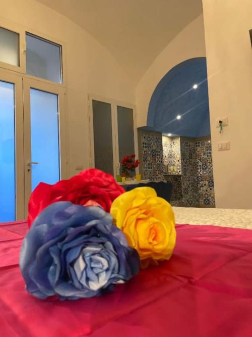 Rose decorative colorate sul letto rosso nella moderna suite di Sorrento con soffitto ad arco e vista sulla città