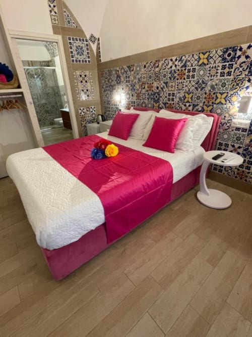 Camera luminosa alle San Nicola Suite Mini Apartments a Sorrento con biancheria rosa, piastrelle decorative e stile moderno