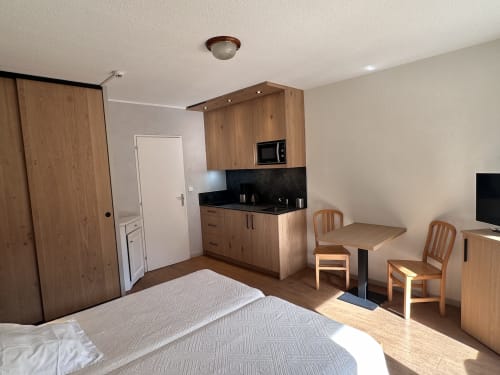 Studio à l'Hôtel Studios La Rochetaillée à Brides-les-Bains avec lit, kitchenette, coin repas et vue sur les montagnes