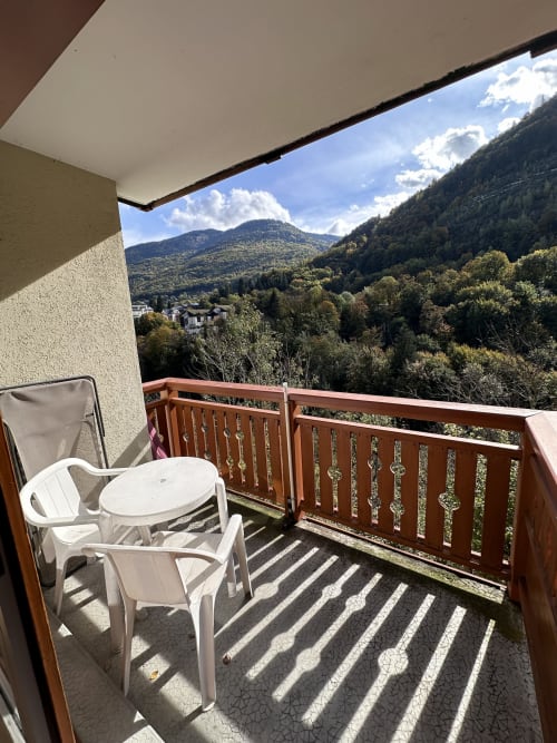 Balcon vue montagne de l'Hôtel Studios La Rochetaillée à Brides-les-Bains avec chaises et table blanches
