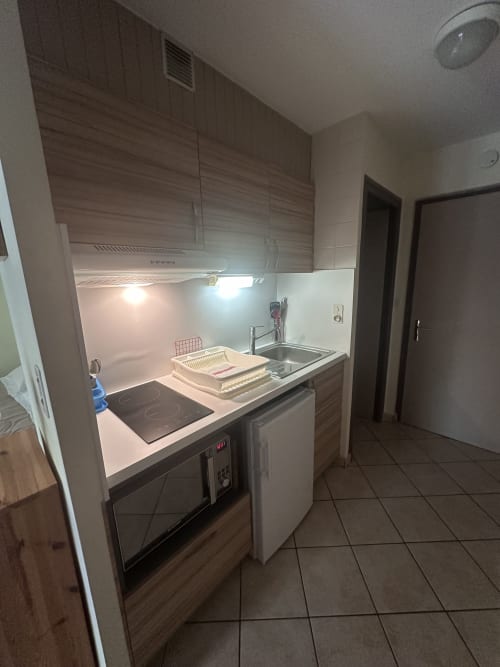 Kitchenette moderne à Brides-les-Bains avec cuisinière, évier et appareils encastrés