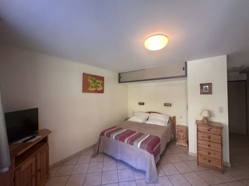 Chambre lumineuse aux Studios La Rochetaillée à Brides-les-Bains avec lit, TV, mobilier bois et design moderne