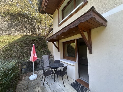 Patio de l'appartement aux Studios La Rochetaillée avec sièges, parasol rouge et vue sur les montagnes à Brides-les-Bains