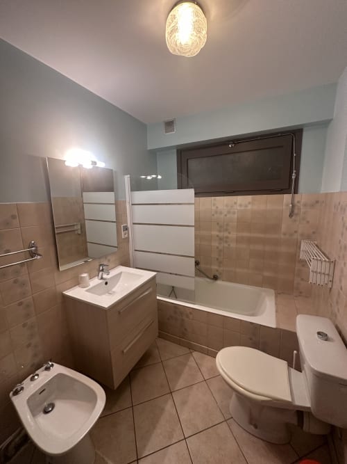 Salle de bains moderne aux Studios La Rochetaillée à Brides-les-Bains avec baignoire, lavabo et toilettes