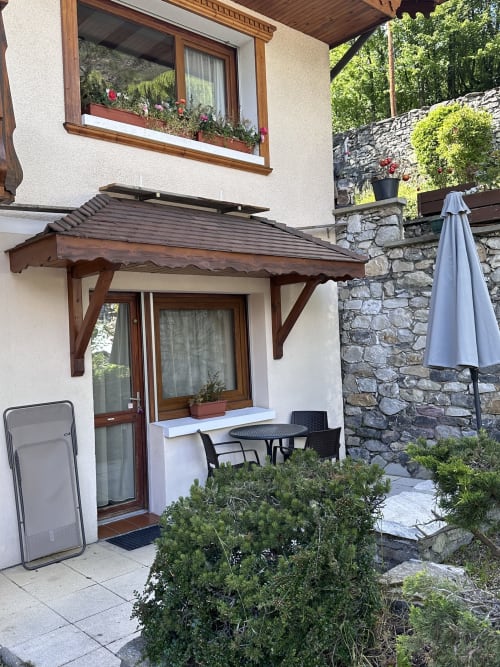 Terrasse de l'appartement Hôtel Studios La Rochetaillée avec vue sur les montagnes, pergola en bois, coin repas et murs en pierre