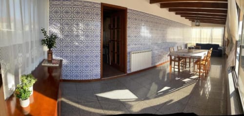 Espaçosa sala de estar em Casa Da Avó Ilda em Matosinhos com paredes revestidas de azulejos, mesa de jantar, vigas de madeira e luz natural