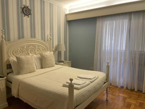 Quarto elegante com cama creme, papel de parede listrado e vista para o oceano em Casa Da Avó Ilda em Matosinhos